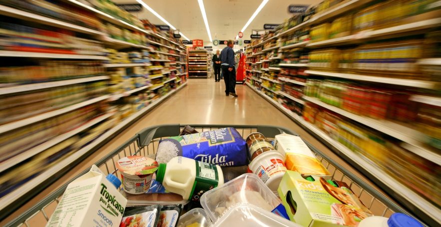Carrito de compras en un pasillo de supermercado con productos variados.